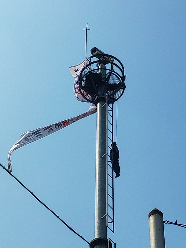 12일 오전 8시30분께 대구 남구 영대병원네거리 인근 CCTV 첨탑에 한 남성이 올라가 인형을 매달고 시위를 하고 있다.전영호기자