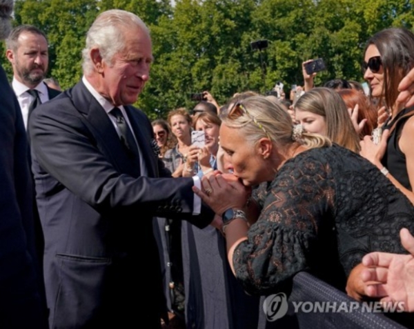 9일(현지시간) 영국 버킹엄궁 앞에서 한 여성이 찰스 3세 국왕의 손에 키스하고 있다. 연합뉴스
